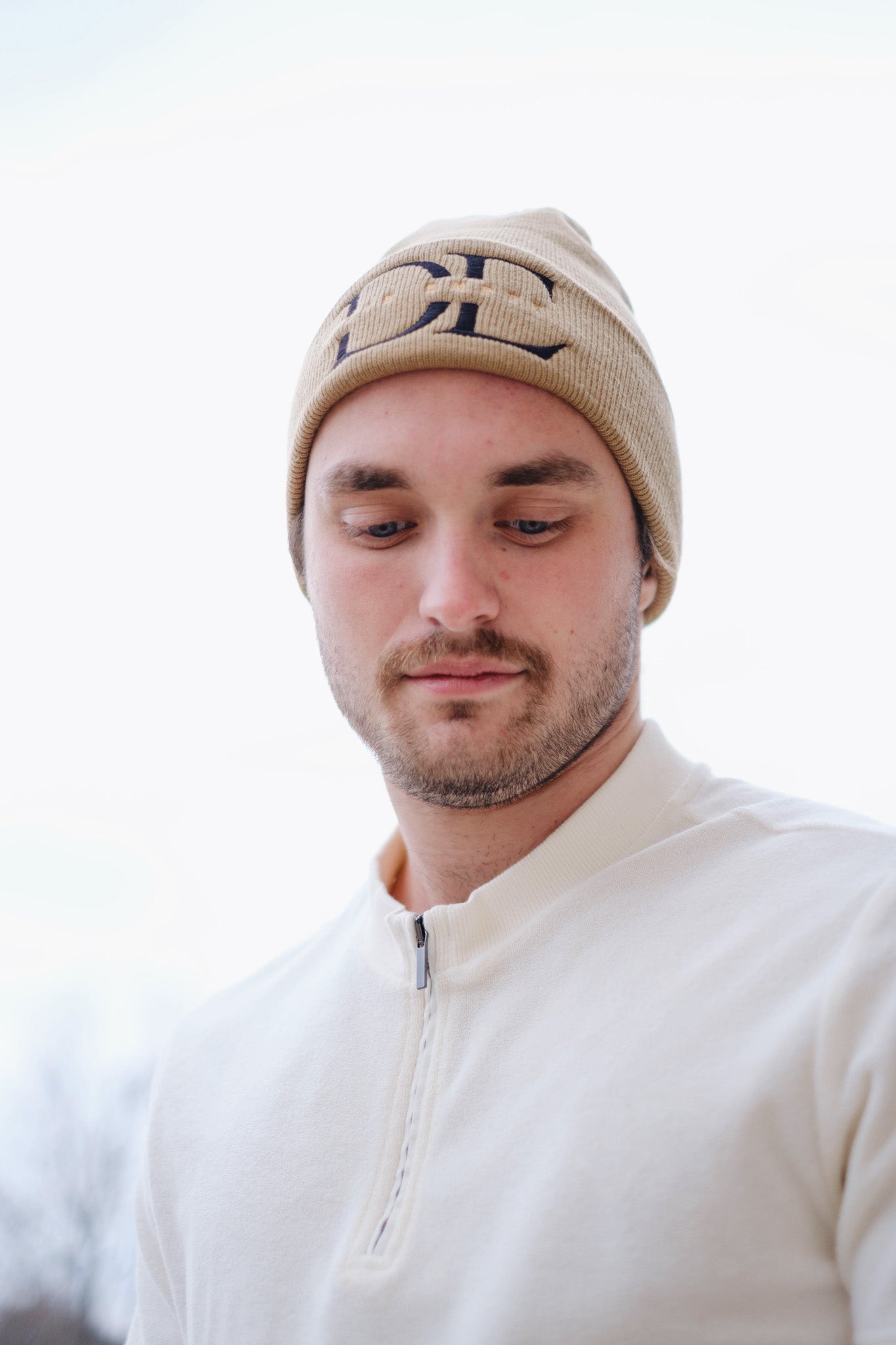 frontal image of beige Die Empty Beanie on a caucasian male model taken from a low angle