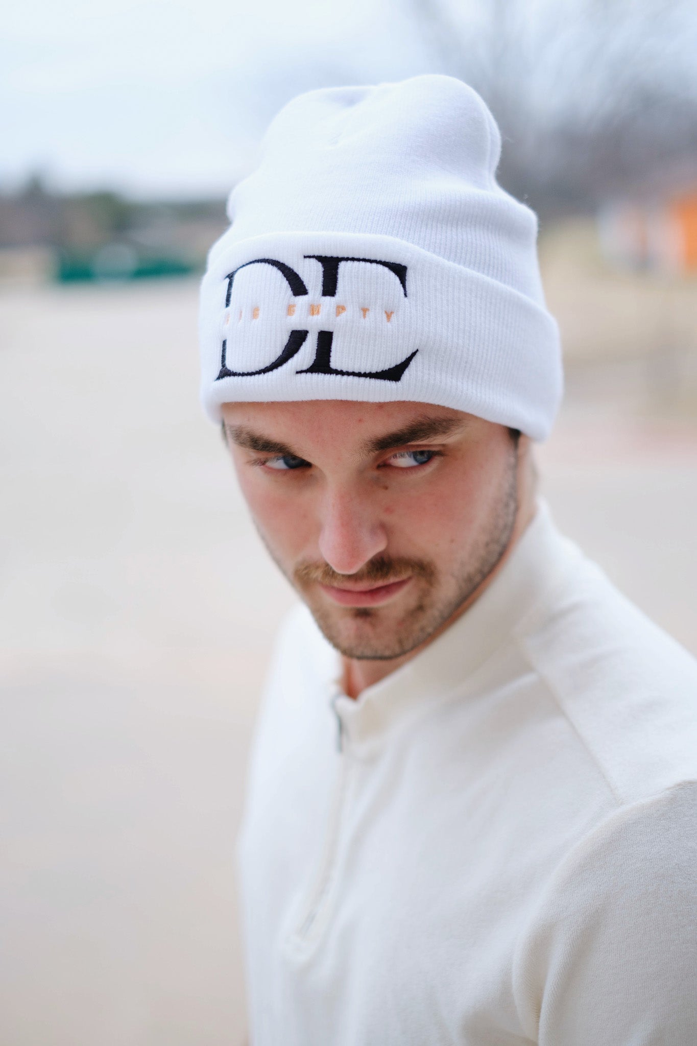 frontal image of White Die Empty Beanie on a caucasian male model taken from a high angle