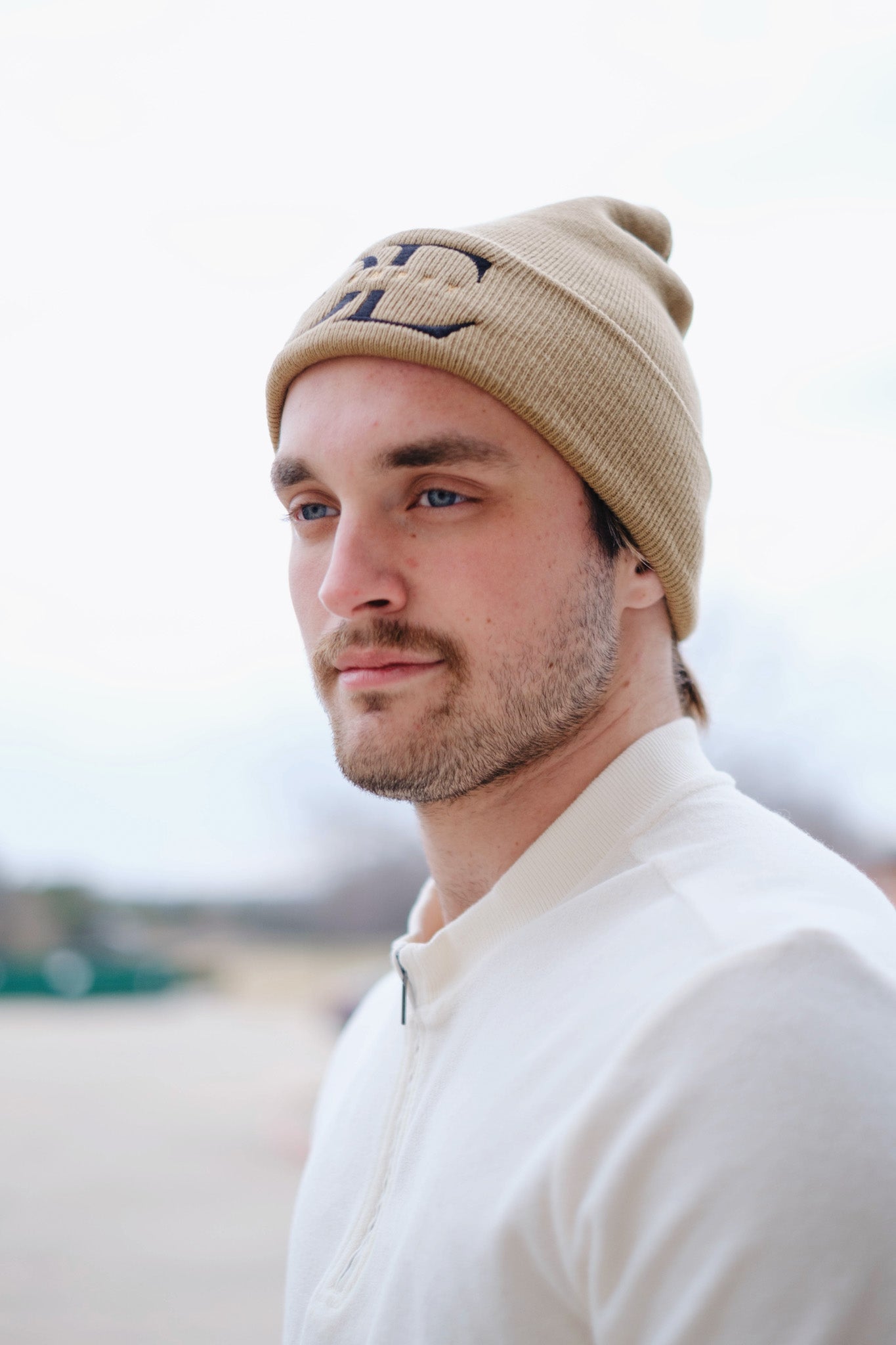 frontal image of beige Die Empty Beanie on a caucasian male model taken from a side angle